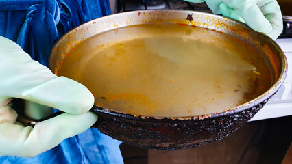 Dirty greasy pan after cooking. Housewife holding dirty pan with water,washing dishes.
