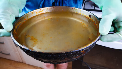Dirty greasy pan after cooking. Housewife holding dirty pan with water,washing dishes.