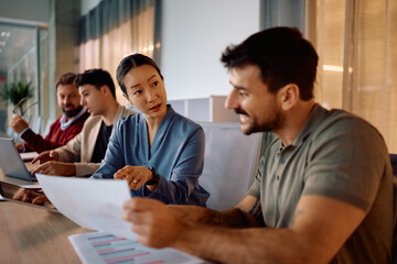 Korean CEO and her colleague going through business reports on a meeting in the office.