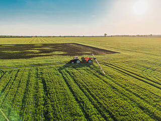 Tractor spray fertilizer on green field aerial view. 