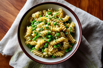 Fresh pasta with peas served in a rustic bowl placed on a wooden table with a linen cloth underneath