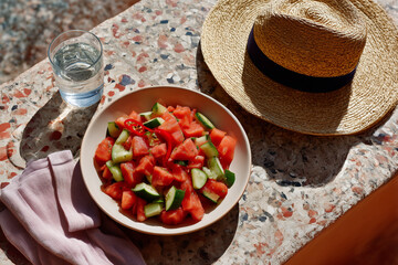 Refreshing summer salad with watermelon and cucumber on a sunny outdoor table