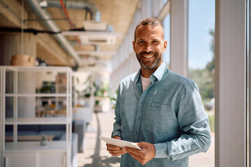 Portrait of happy businessman using digital tablet in the office looking at camera.