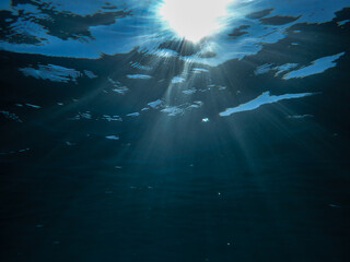 Light filtering down through blue water. Underwater sunlight in deep sea. Light viewed from blue...