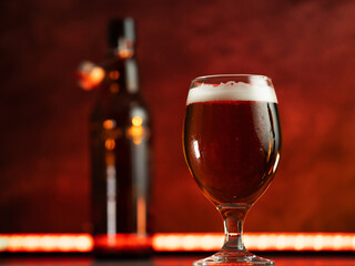 Glass of cold beer on table, beer bottle and back light