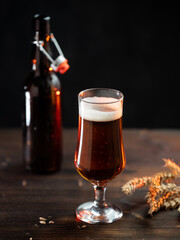 Cold beer glass on wooden table, beer bottle and wheat ears