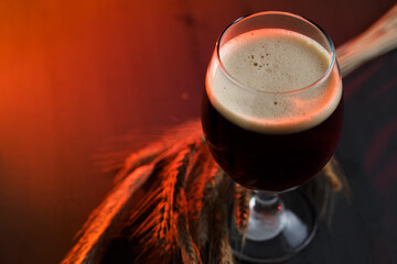 Stout beer glass on wooden table with rye ears. Copy space