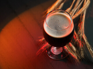 Stout beer glass on wooden table with rye ears. Copy space