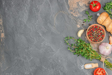 A rustic flatlay of herbs, spices, and vegetables on a dark stone background, ideal for cooking,...
