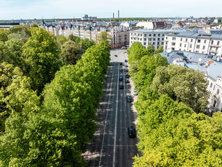 A tree lined avenue bordered by historic European style buildings with ornate facades, sloped...