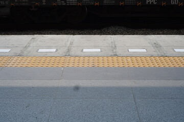 Tactile Paving and Train Car Detail: A Textured Perspective of a Train Station Platform
