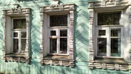 Carved architraves on windows of wooden building. Traditional decor of Russian houses. Three...
