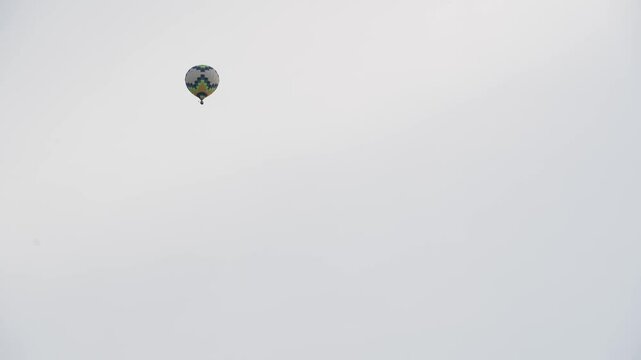 A hot air balloon with a basket flies across the evening sky. The silhouette of a balloon against the background of the evening sky on a white sky.