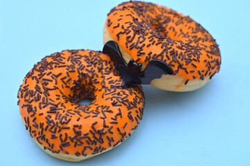 orange donuts with chocolate sprinkles and a bat for Halloween close-up