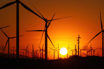Palm Springs Windmills at Coachella Valley, California, USA at sunset against orange sky