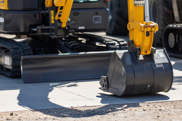 close up of heavy duty excavator bucket on construction site with tracked vehicle in background, industrial digging equipment for building, earthmoving, demolition, and infrastructure development