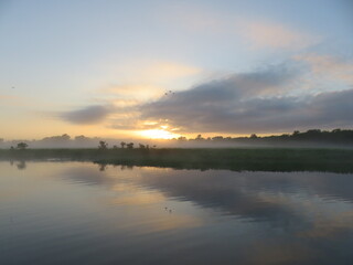 Fototapeta premium Sunrise with mist across still water