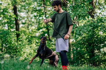 Dog trainer playing with doberman pinscher in park