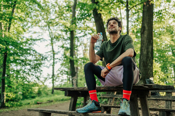 Trail runner resting and drinking water in forest