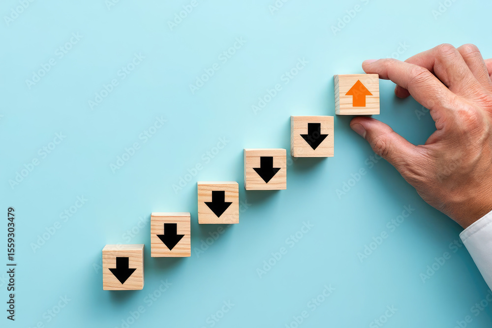 Poster conceptual image of wooden blocks with arrows showing a shift from downward to upward trend on a blu