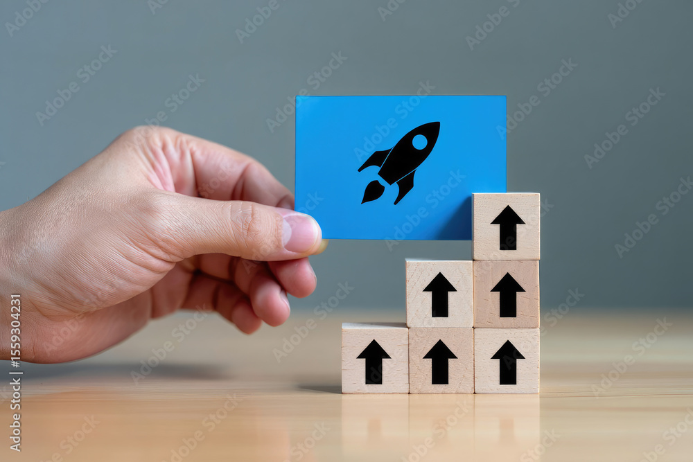 Poster visualizing startup success a hand holding a rocket icon card placed on top of wooden blocks arrange