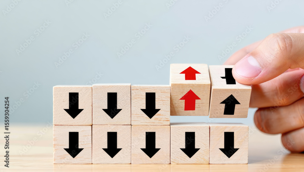 Poster hand placing a wooden block with an upward arrow among blocks with downward arrows, symbolizing a sh