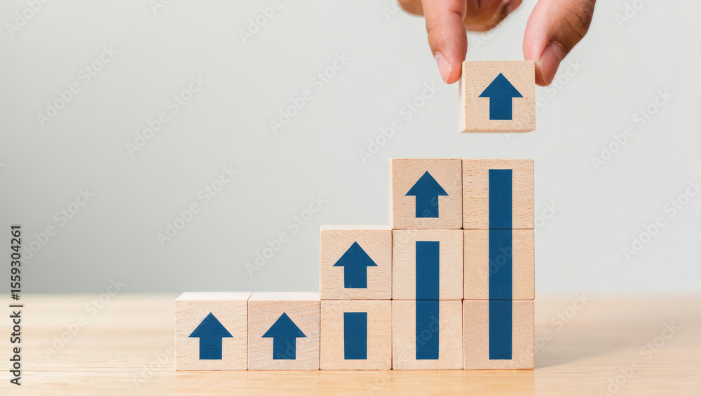 Poster hand placing a wooden block with an upward arrow on top of a stacked bar graph symbolizing growth an