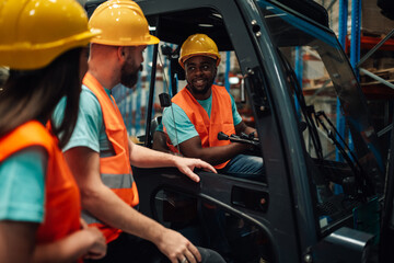 Warehouse workers talking with forklift driver