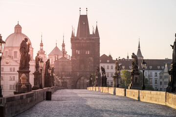 Early morning light bathes Charles Bridge in a golden hue, illuminating its historic statues and...