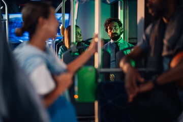Passengers sitting and standing on a moving bus at night