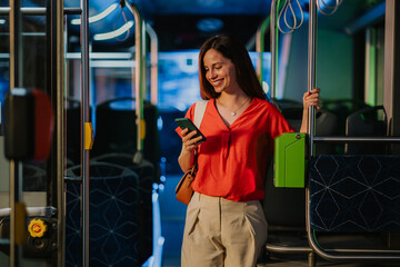Young woman using smartphone on a modern bus at night