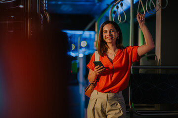 Businesswoman using smartphone on a night bus ride home