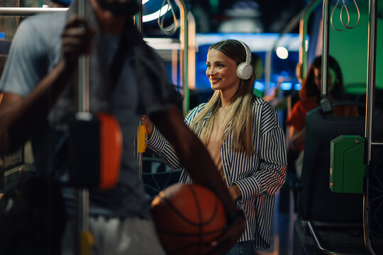 Young woman listening music on headphones while riding bus at night