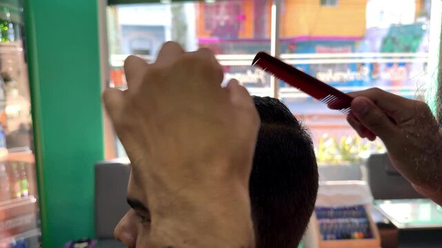 Hairdresser combing client's hair in beauty salon