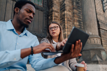 Business colleagues collaborating on laptop outside church building