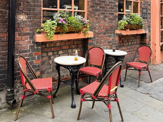 Outdoor cafe seating with red chairs and flower boxes against a brick wall in Liverpool, England, UK