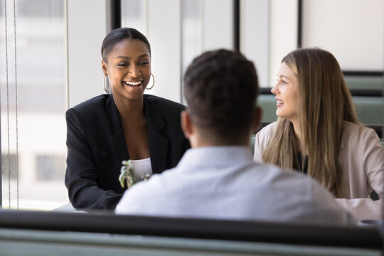 Friendly communication. Relaxed diverse multiethnic office workers team gather at table in cozy cafe chatting having fun discuss successful project results with joy laughter during casual conversation