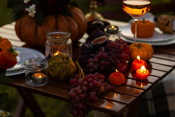 Beautiful elegant autumn table setting for thanksgiving family dinner or wedding. Orange pumpkin with flowers as centrepiece. Cozy fall home atmosphere. Wineglass, romantic marriage proposal, sunset