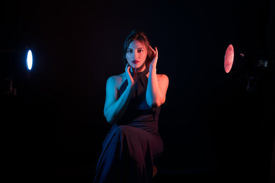Portrait of Woman Fashion Model wearing a black dress  in Color Gel Studio Lighting