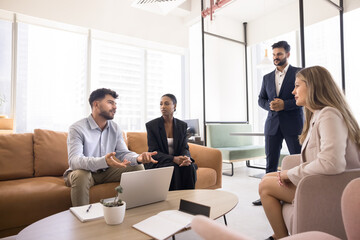 Informal business brainstorming. Focused millennial man ceo corporate leader diverse multiethnic team listen to young male executive presenting project plan expressing opinion on casual work briefing