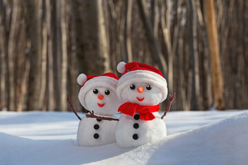 View of a couple of snowmen in a santa hats on their heads in a winter forest. Holiday christmas...