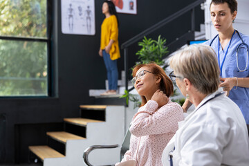 Doctor consulting patient about neck pain symptoms during medical appointment at hospital lobby....