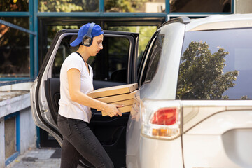 Female city courier carrying massive stack of pizza boxes delivering fast food order from a...