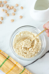 Hand is holding a spoon with chickpea flour. Top view.