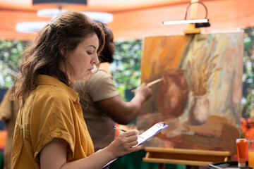 Skilled master painter keeps account of her apprentice techniques, following his creative process...