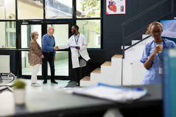 Old male patient receives treatment plan recommendations from black doctor during appointment in...
