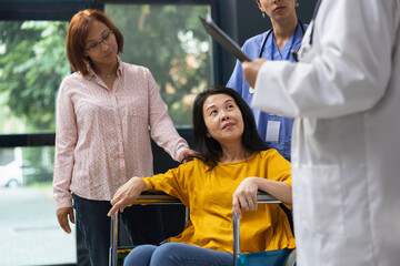 Healthcare medic supporting woman in wheelchair during routine appointment at inclusive clinic....