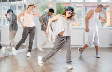 Fototapeta premium Positive young lady engaged in hip-hop together with other attendees of dancing courses