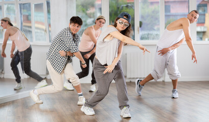 Active young girl practicing basic hip-hop steps in training hall during dancing classes