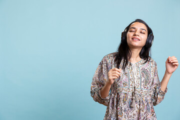 Cheerful young person listening and dancing on music with headset, singing lyrics and moving around...